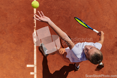 Image of Top view of a professional female tennis player serves the tennis ball on the court with precision and power