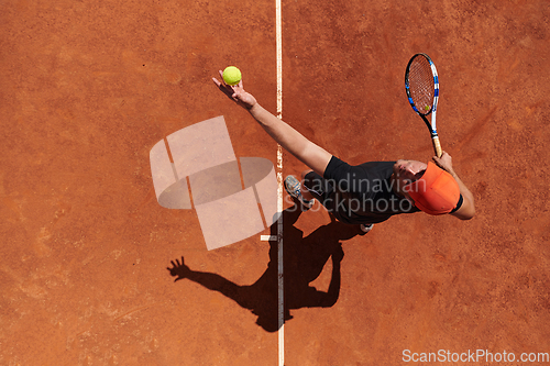 Image of Top view of a professional tennis player serves the tennis ball on the court with precision and power