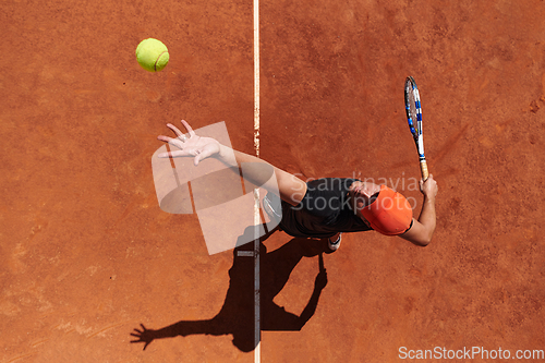 Image of Top view of a professional tennis player serves the tennis ball on the court with precision and power