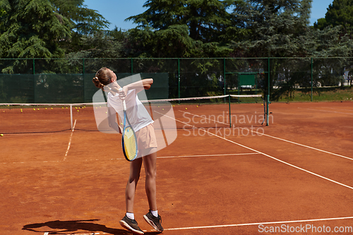 Image of The tennis player focuses intently, perfecting her serve on the tennis court with precision and determination, displaying her dedication to improving her skills.