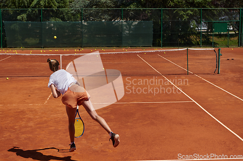 Image of The tennis player focuses intently, perfecting her serve on the tennis court with precision and determination, displaying her dedication to improving her skills.