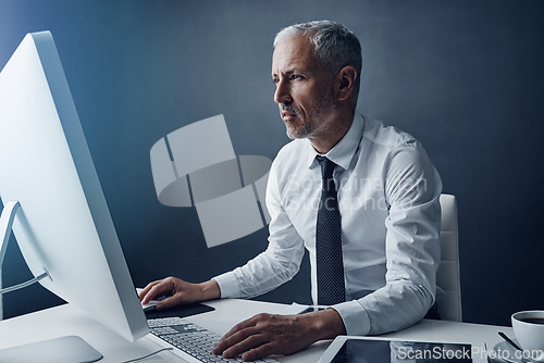 Image of Typing accountant, computer and senior man in studio, working and isolated on a dark background mockup. Focus, writing and serious manager at desktop for reading email, research or business auditor.