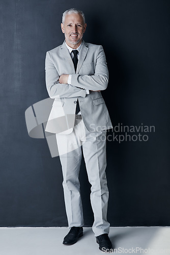 Image of Studio portrait of mature man in suit, arms crossed and smile on dark background. Confidence, pride and professional career for happy executive businessman or senior business owner or successful ceo.