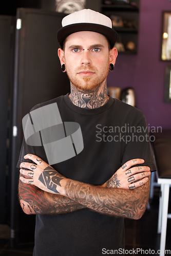 Image of Punk, tattoos and portrait of a male artist standing with crossed arms for confidence in his studio. Serious, cool and face of grunge man with edgy, funky and body art or ink creative business store.