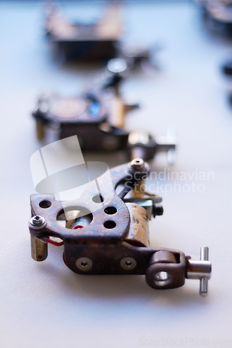 Image of Tattoo, machine and closeup with tools on table for creativity with parts for supply and instrument. Ink, tool or gun and metal for body art with machinery at tattooing studio with desk or device.
