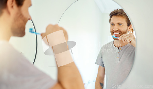 Image of Brushing teeth, dental and mirror with man in bathroom for self care, oral hygiene and morning routine. Cleaning, smile and health with face of male person at home for beauty, wellness and toothbrush