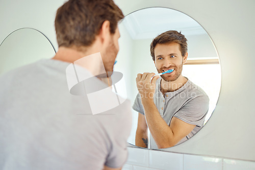 Image of Brushing teeth, morning routine and mirror with man in bathroom for self care, oral hygiene and dental. Cleaning, smile and health with face of male person at home for beauty, wellness and reflection