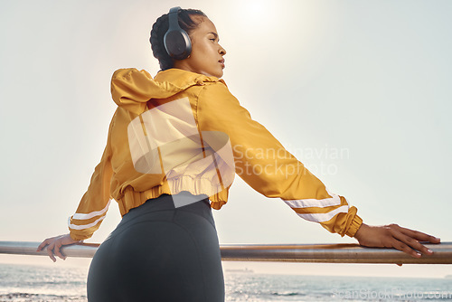 Image of Headphones, thinking and woman at ocean for exercise, fitness or running mindset, goals and inspiration music. Health, podcast and athlete, runner or sports person behind by beach listening to audio