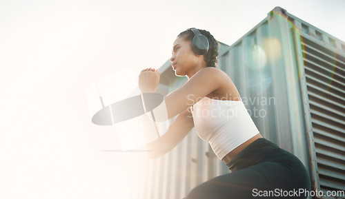 Image of Fitness, woman with headphones and training with lens flare for motivation. Exercise or workout, health wellness or cardio and young female athlete squat in sportswear for healthy lifestyle