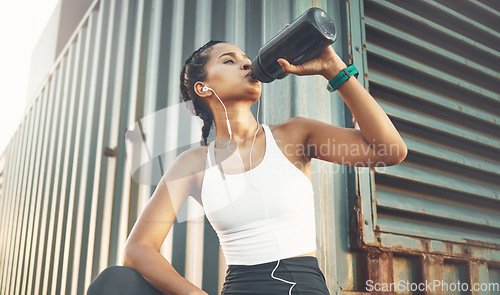 Image of Fitness, woman drinking water and listen to music for motivation. Training or exercise, workout in sportswear or hydration and female athlete holding bottle for health wellness with lens flare