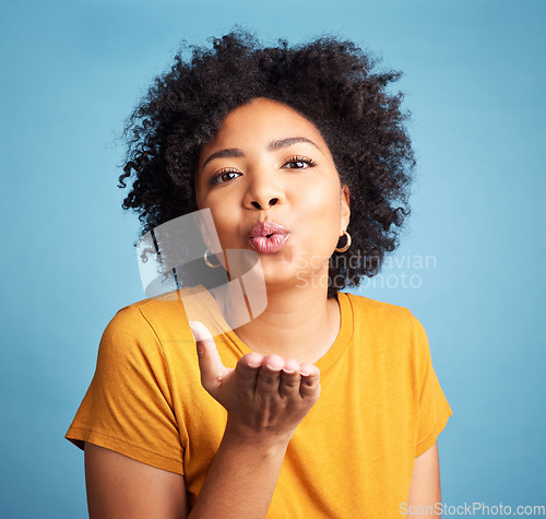 Image of Woman, blowing kiss and beauty with makeup, flirt in studio with t shirt isolated on blue background. Young female model, cosmetics and pout, emoji and care free with casual fashion and gen z youth