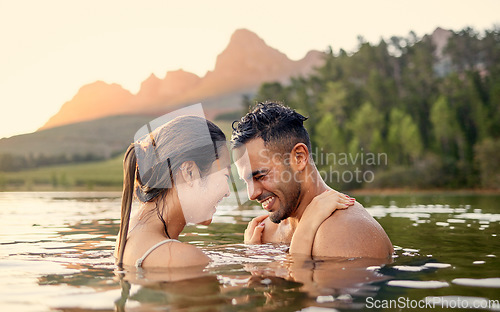 Image of Man, woman and hug with swim in lake, sunset and forest with love, bonding and vacation in summer. Young happy couple, outdoor and water for holiday together in sunshine with care, laugh or freedom