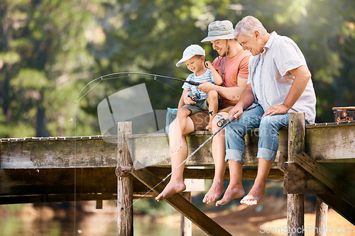 Image of Dad, grandfather and teaching child fishing at lake together for fun bonding, lesson or activity in nature. Father, grandpa and kid learning to catch fish with rod by water pond or river in forest