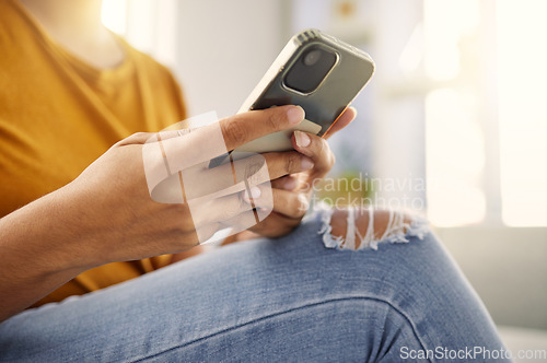 Image of Phone, sofa and casual person hands typing, search or reading social media, communication or networking at home. Couch, relax and people in jeans on smartphone, mobile chat or internet in living room