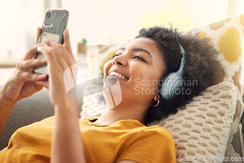 Image of Relax, couch and woman with a smartphone, headphones and home with happiness, stress relief and streaming music. Smile, female person or girl on a sofa, headset and chilling with a cellphone and song