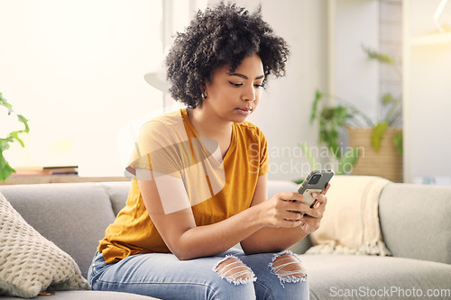 Image of Phone, relax and woman on sofa in home living room for social media, internet scroll or texting. Mobile, serious or African person on couch in lounge for online app, website or reading email in house