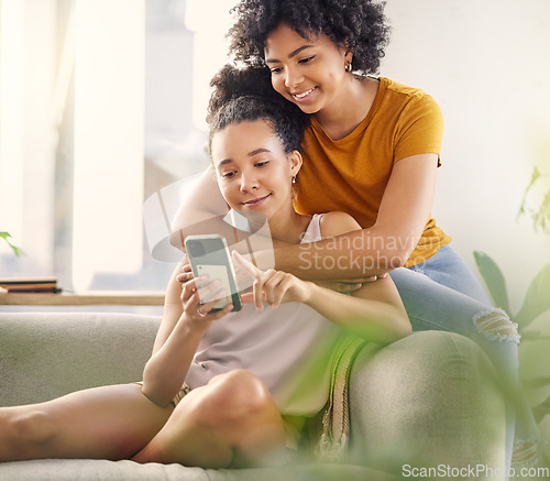 Image of African lesbian couple, sofa and phone with texting, social network app and relax with meme in living room. Women, together and smartphone for chat, contact or watch internet video on lounge couch