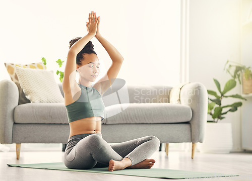 Image of Yoga, fitness and meditation with a woman on an exercise mat in the living room of her home for wellness. Pilates, mental health and zen with a young female yogi sitting on the floor for inner peace