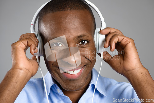 Image of Music, portrait of a black man with headphones and against studio background happy listening to radio. Podcast or audio, sound playlist or smile and face of African male person streaming media