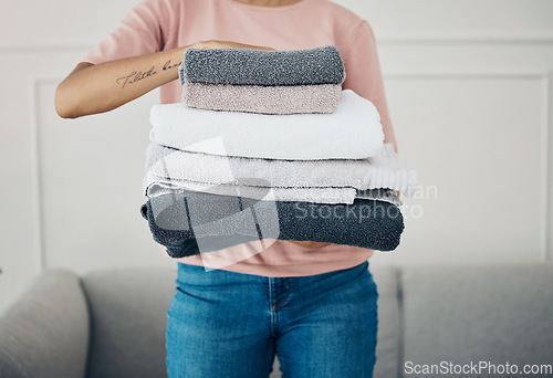 Image of Towels, hands and cleaning with a woman housekeeper closeup in the living room of a home for hygiene. Laundry, housekeeping and chores with a female cleaner carrying a pile of washing in her house