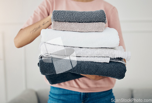 Image of Towels, laundry and cleaning with a woman housekeeper closeup in the living room of a home for hygiene. Hands, housekeeping and chores with a female cleaner carrying a pile of washing in her house