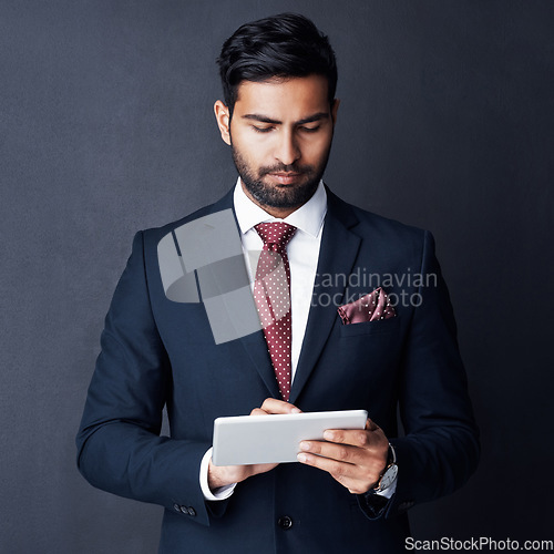 Image of Serious, business man and tablet in studio, dark background and app for trading, planning or internet research. Corporate broker, indian male trader or focus on digital technology, online and website