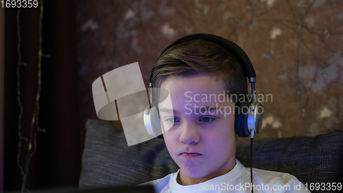 Image of Kid boy or teen learning at home on laptop for school.