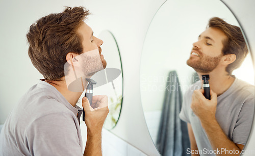 Image of Mirror reflection, grooming and man shaving in the bathroom of a home in the morning for personal hygiene. Electric razor, skincare and routine with a young male person in his house for hair removal