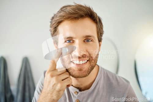 Image of Bathroom, portrait and happy man with skincare cream for acne treatment, skin hydration or home beauty routine. Face cosmetics, dermatology smile or hygiene person with morning sunscreen application