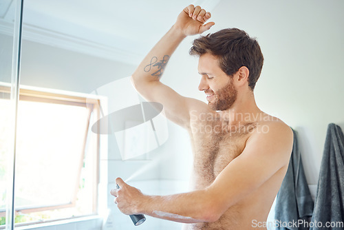 Image of Man, spray and deodorant for underarm in bathroom with smile, wellness and hygiene to start morning. Young guy, happy and aerosol fragrance for cleaning, armpit and perfume for health in apartment