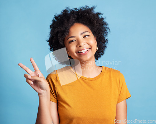 Image of Peace sign, portrait of a woman with smile and against a blue background for satisfaction. Positivity or cheerful, health wellness and face of happy female person pose against studio backdrop