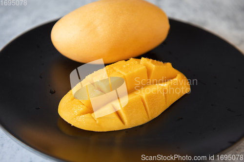Image of Fresh yellow mango fruit in a black plate