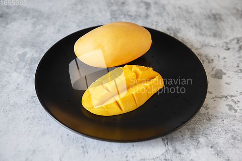 Image of Fresh yellow mango fruit in a black plate