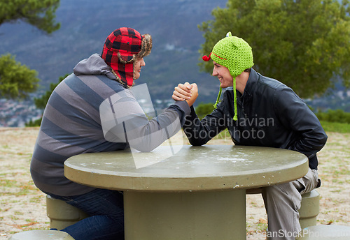 Image of Arm wrestling, happy friends and outdoor at table for sports, challenge and exercise. Strong, conflict and men holding hands for competition, power and muscle match, training or workout in park.