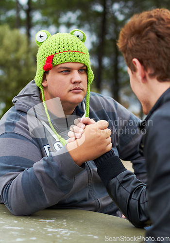 Image of Arm wrestling, friends and outdoor at table for sports, challenge and exercise. Strong, conflict and men holding hands for competition, serious power and muscle match, training or workout in park.