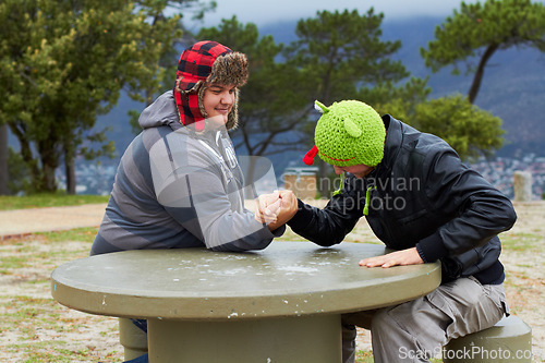 Image of Arm wrestling, friends and winning outdoor at table for sports, challenge and exercise. Strong, conflict and men holding hands for competition, power and muscle match, training or workout in park.