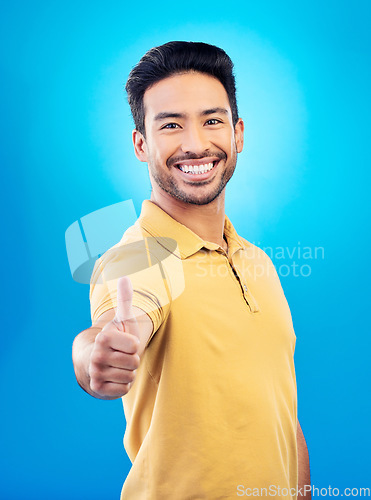 Image of Thumbs up, success portrait and man on blue background for thank you, winning or yes, like emoji and social media subscribe. Winner, person or asian model in okay, support or good job sign in studio