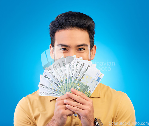 Image of Money, winner and man cover face isolated on blue, studio background for winning, cash fan or financial loan. Lottery, bank and asian person winning bonus, budget secret or finance profit in portrait