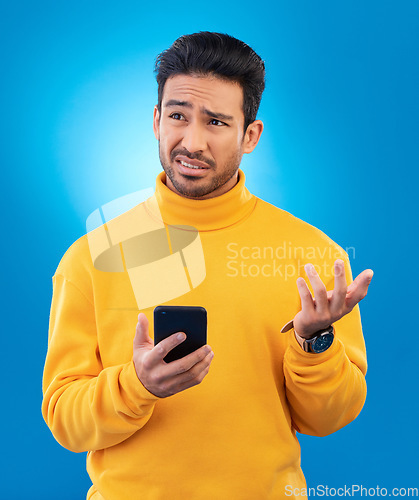 Image of Scam, error and Asian man with a smartphone, confused and internet issue against a blue studio background. Male person, guy and model with a cellphone, doubt and decision with connection problems