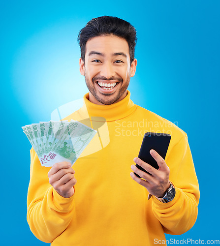Image of Success, money and portrait of Asian man with phone in studio for online bonus, competition and lottery. Winner, finance and male person on blue background with cash for promotion, winning and deal