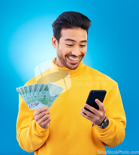 Image of Man, phone and money in studio with prize, esports gambling or happy for success by blue background. Young asian guy, student and smartphone with cash, fintech or crypto with profit, bonus or goals