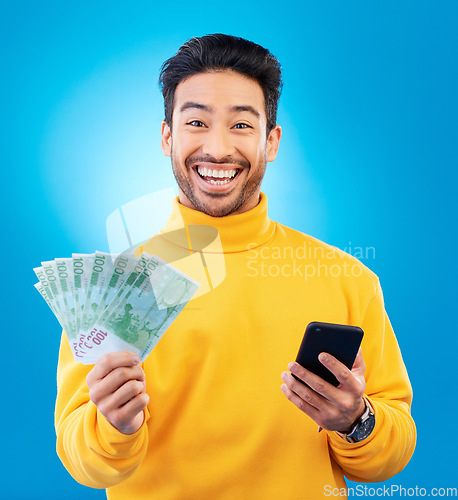 Image of Man, phone and money fan in studio with prize, esports gambling or happy in portrait by blue background. Young asian guy, winner and cellphone with cash, fintech or crypto with profit, bonus or goals