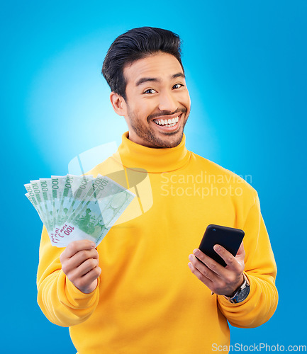 Image of Cash, money and portrait of Asian man with phone in studio for online bonus, competition and lottery. Success, finance and male person on blue background excited for promotion, winning and deal