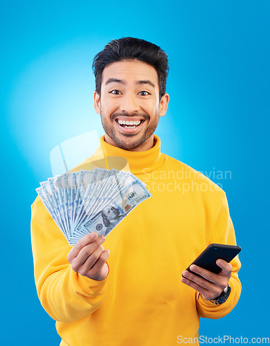 Image of Man, phone and cash fan in studio for prize, esports gambling or excited in portrait by blue background. Young asian guy, winner and smartphone for money, fintech or crypto with profit, bonus or goal