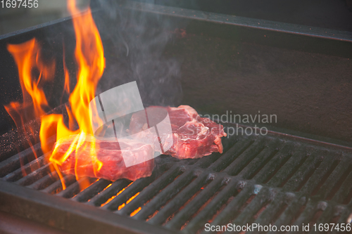 Image of Beef steaks on the grill with flames