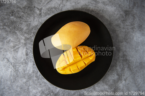 Image of Fresh yellow mango fruit in a black plate