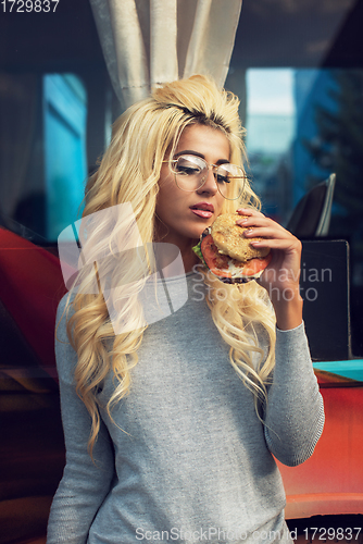 Image of Woman eating a burger and soda water near the food truck