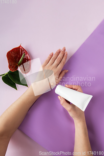 Image of Young woman applying hand cream