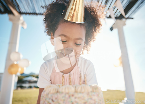 Image of Girl, smile and happy birthday with cake in garden for special event with hat or balloons. Party, dessert and candles for celebration with happiness in outdoor at house in summer for milestone.