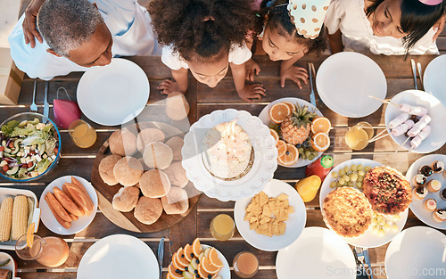 Image of Birthday, party and family with top view with food or children for celebration and eating cake for milestone. Party, parents and kid is blowing dessert on table with feast or joy for special event.